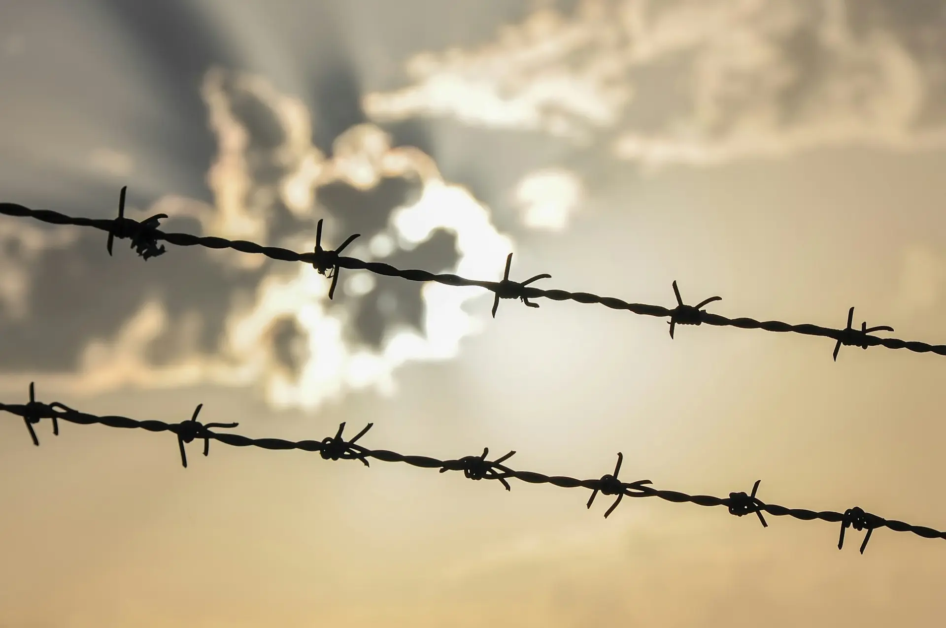 a line of barbed wire with a cloudy sky in the background
